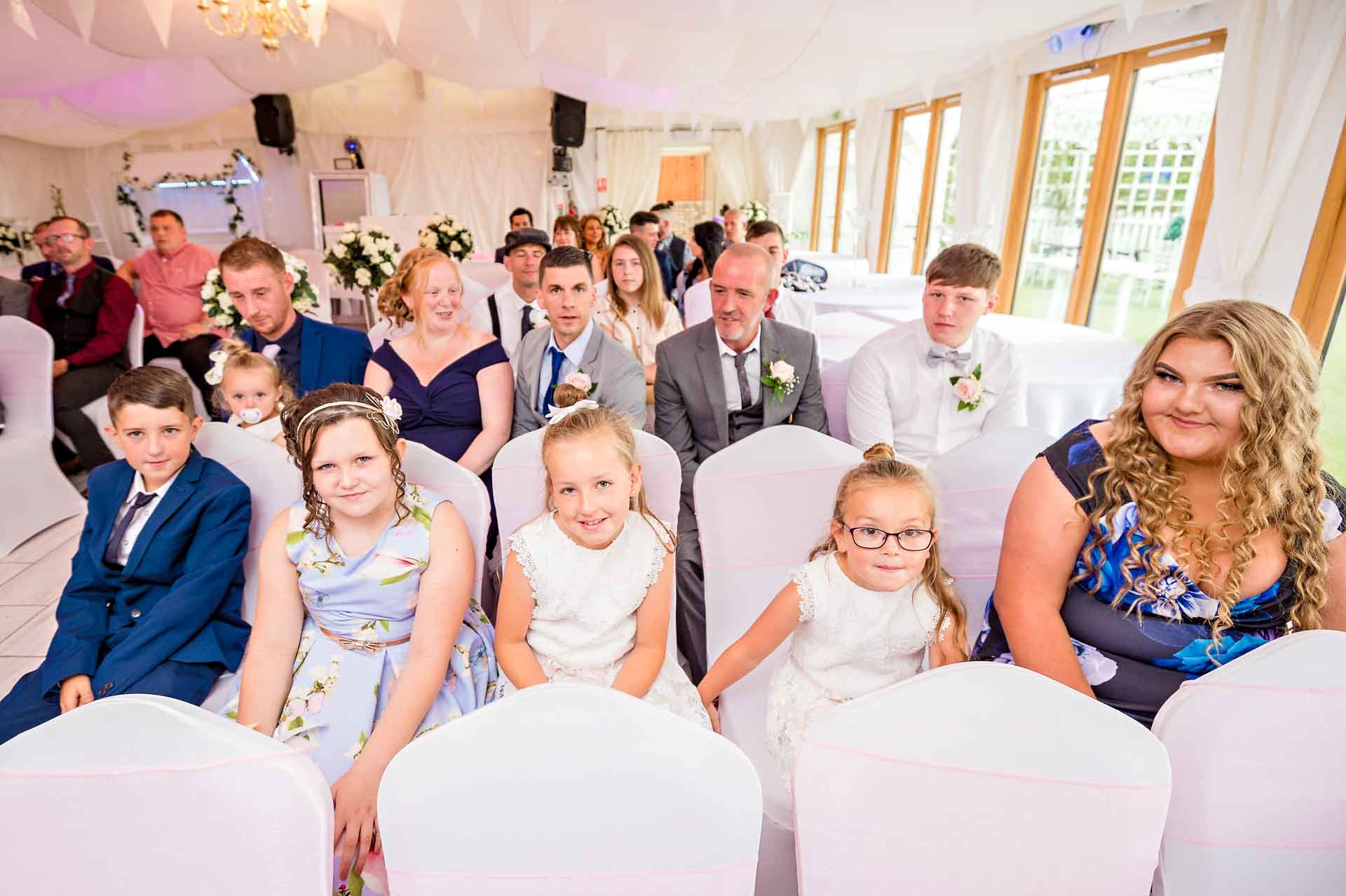 A row of 5 guests waiting for the bride at a wedding in the Marquee at Ridgeway Golf Club