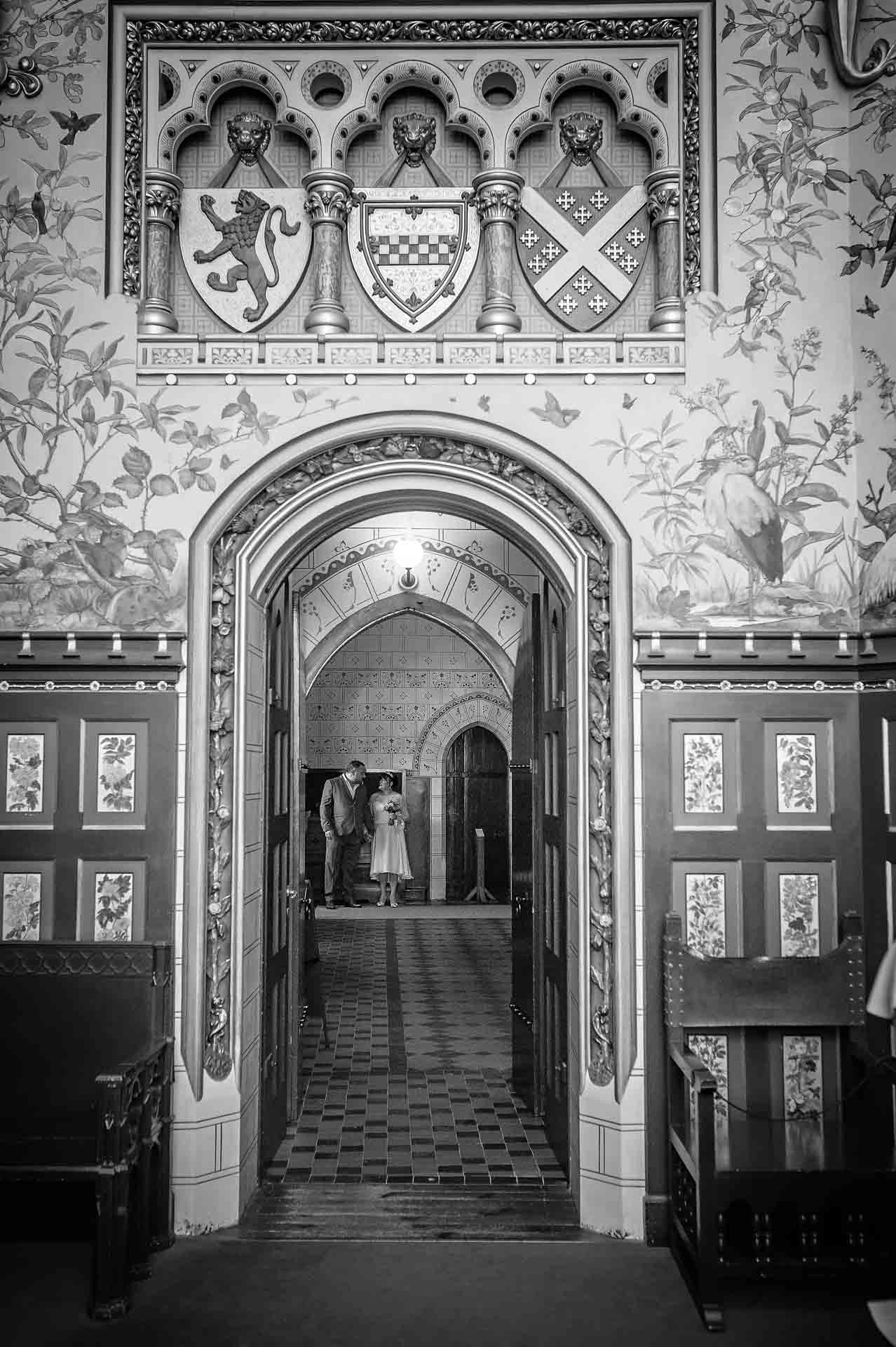 Wedding couple framed through doorway waiting before ceremony in black and white