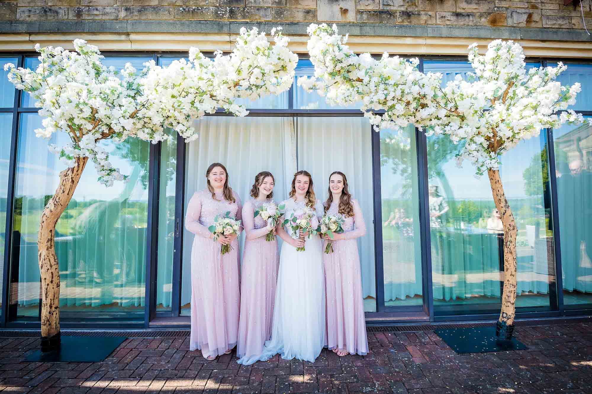 Bride with three bridesmaids in pink outside the Via Julia Suite at Celtic Manor Resort