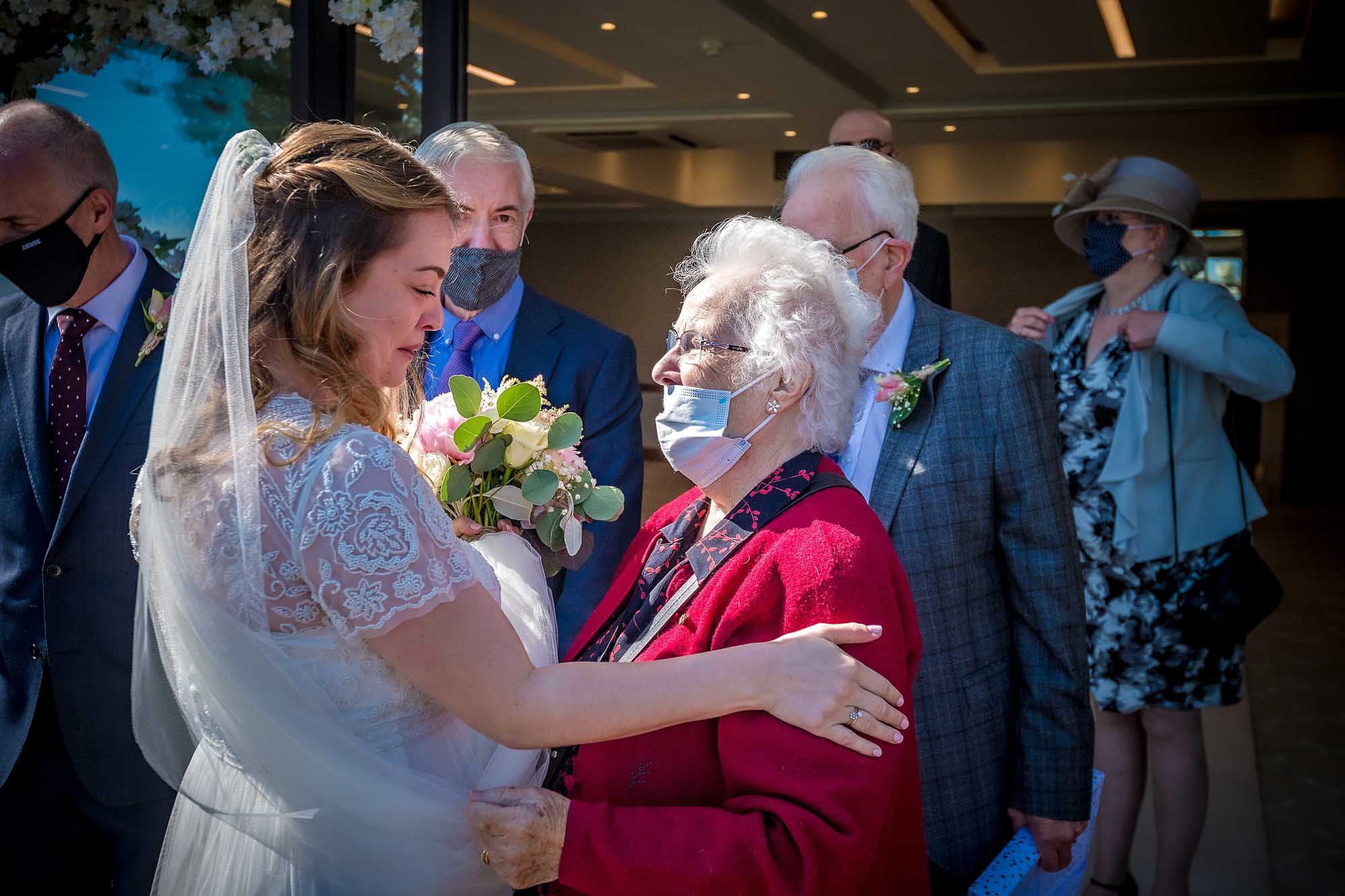 Tearful bride greets Grandma with a tender hand on her arm after wedding ceremony
