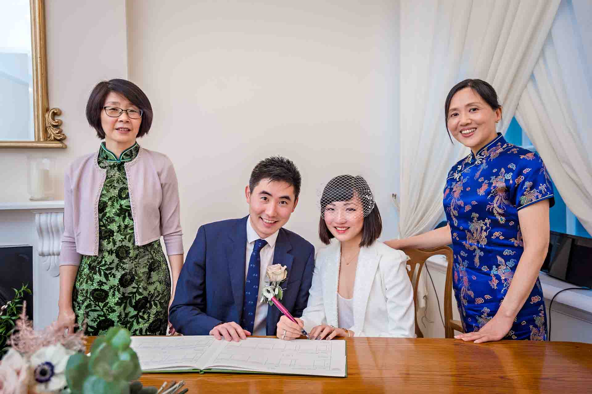 The couple pose with their wedding register and witnesses