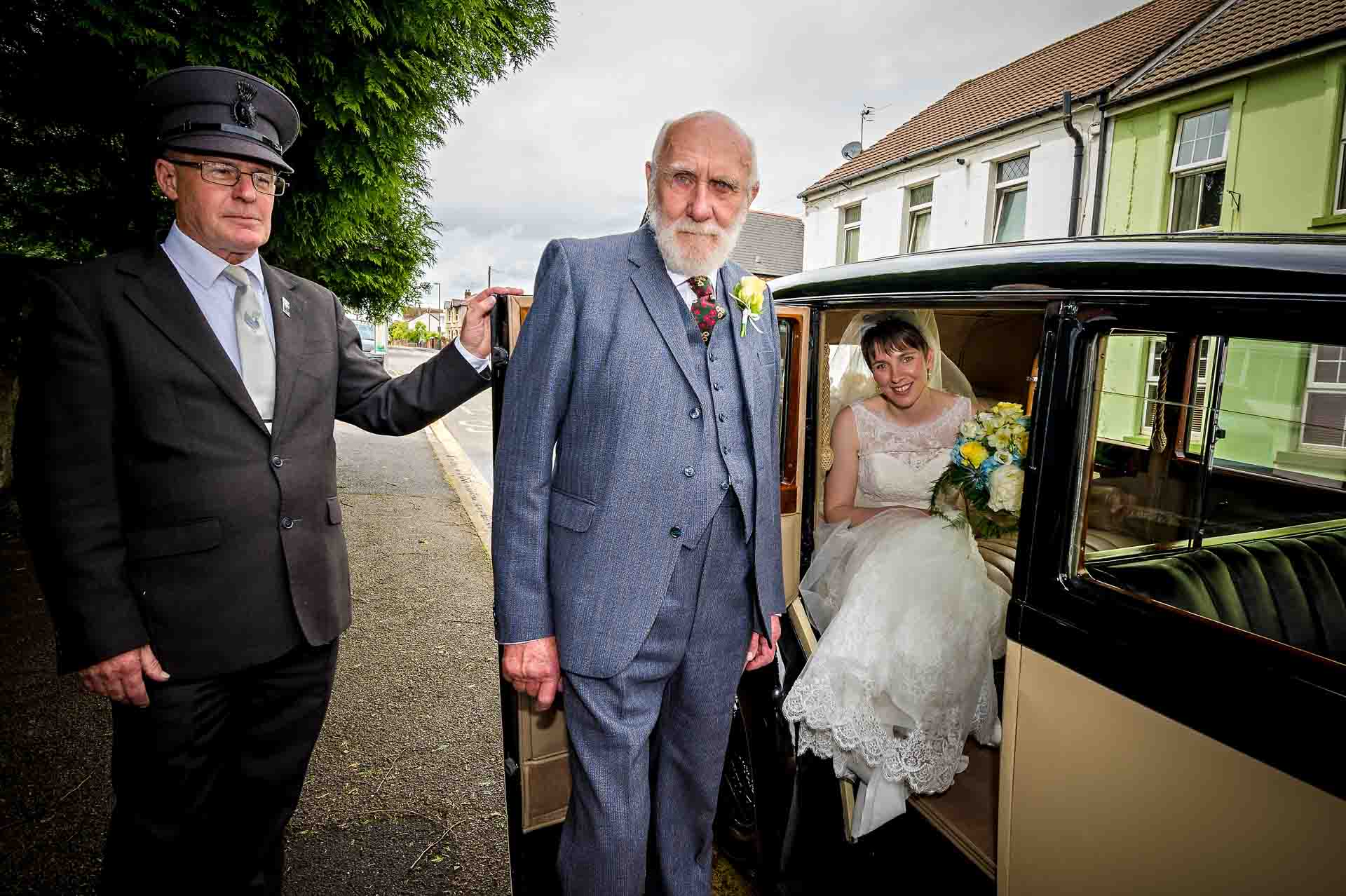 Grandfather standing outside Rolls Royce with Chauffeur and bride seated