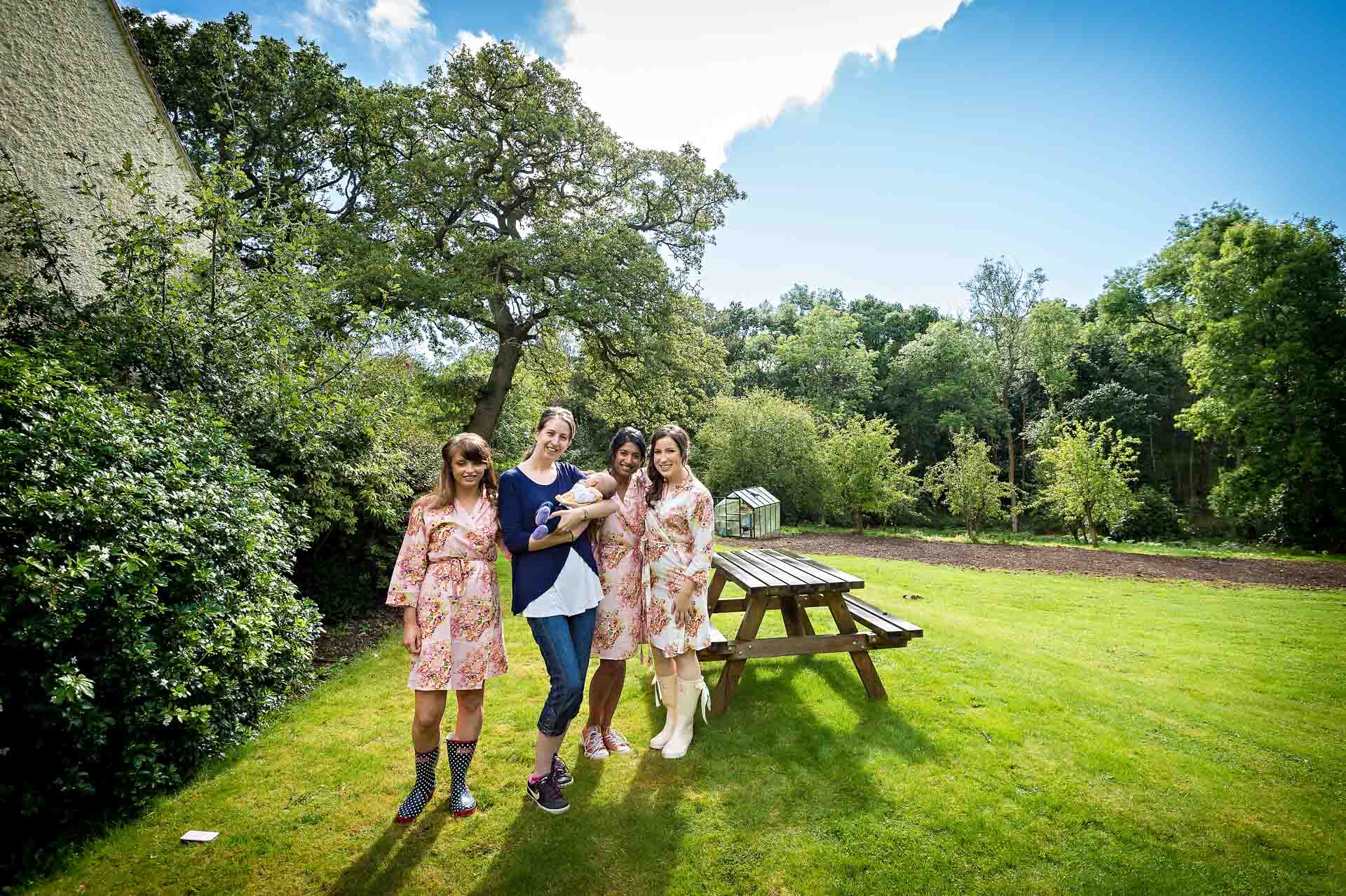 Four women and baby in hotel garden with picnic table in sun