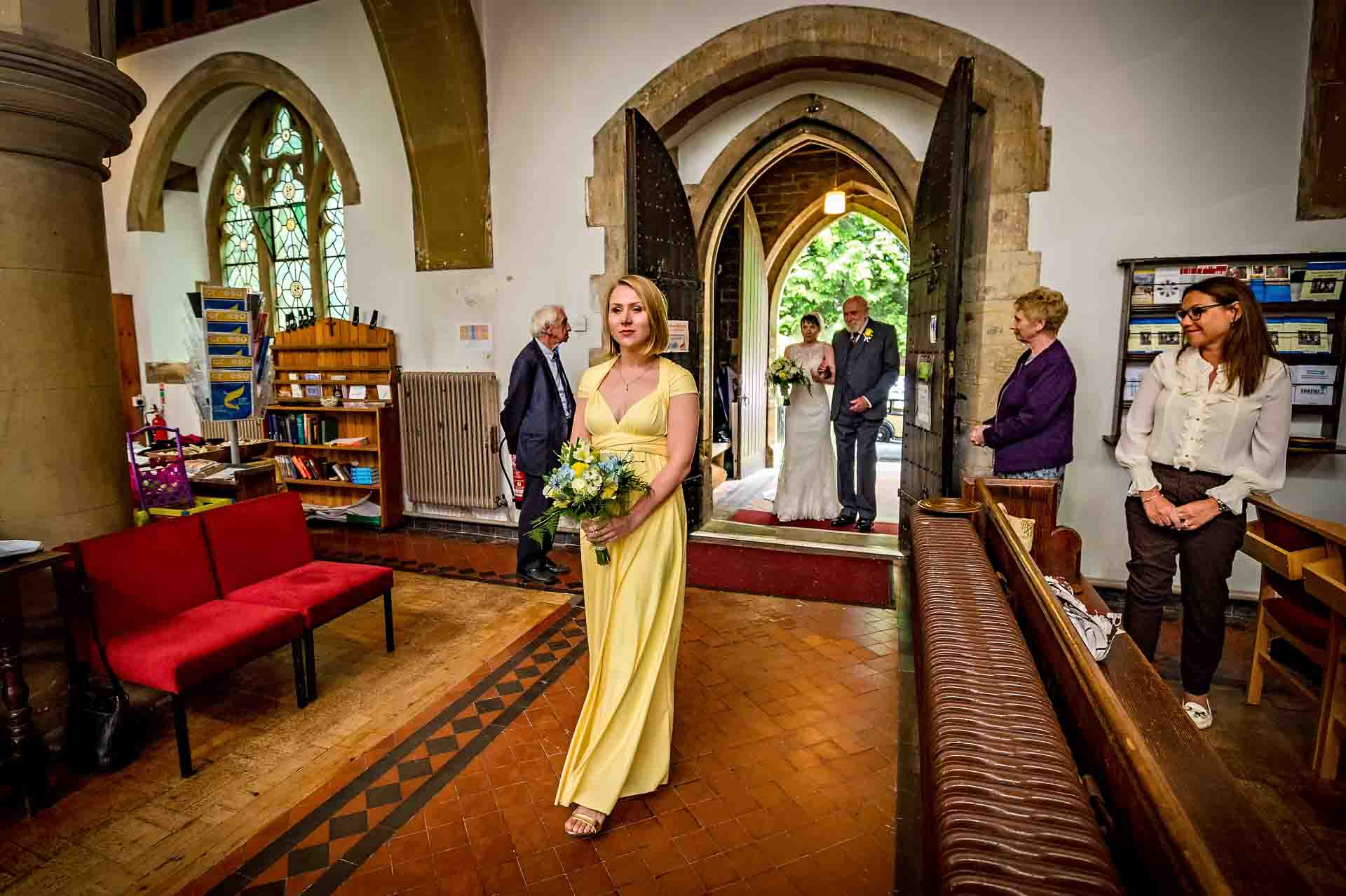 Bridesmaid leading bridal procession at St Martins Church wedding in Caerphilly