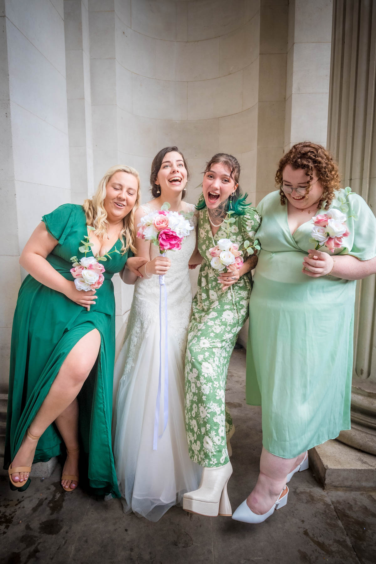 Bride poses with her bridesmaids dressed in green outside Old marylebone Town Hall