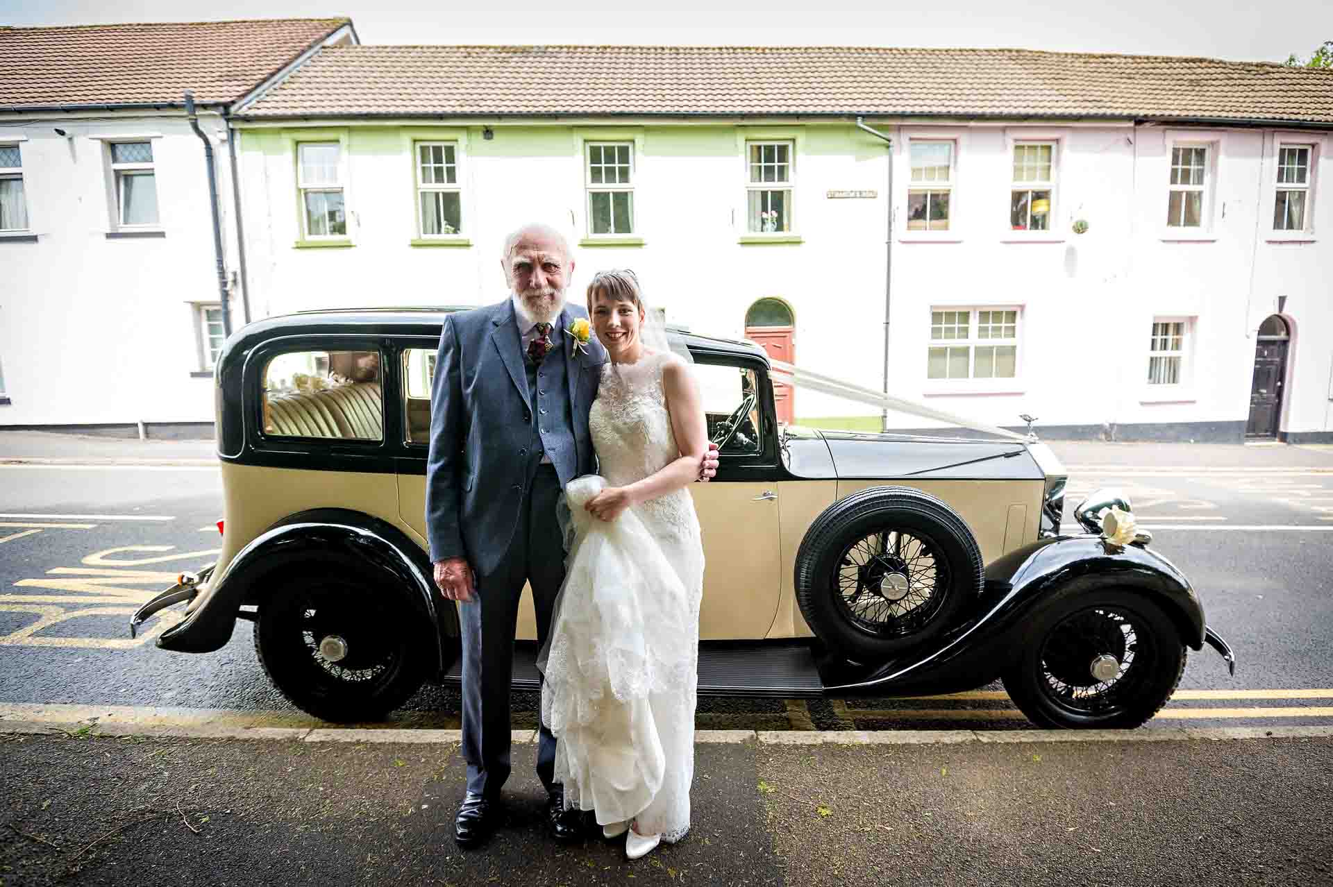 Bride and grandfather pose by Rolls Royce outside St Martins Church, Caerphilly