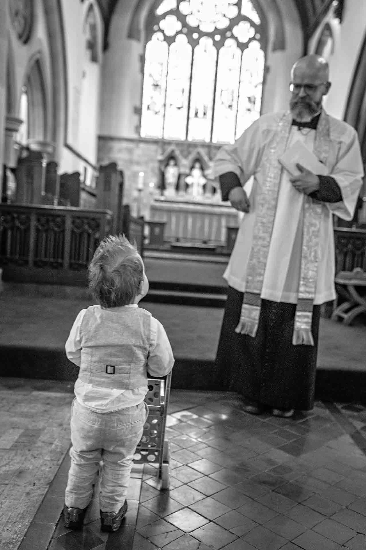 Toddler pushing trolley towards vicar in church