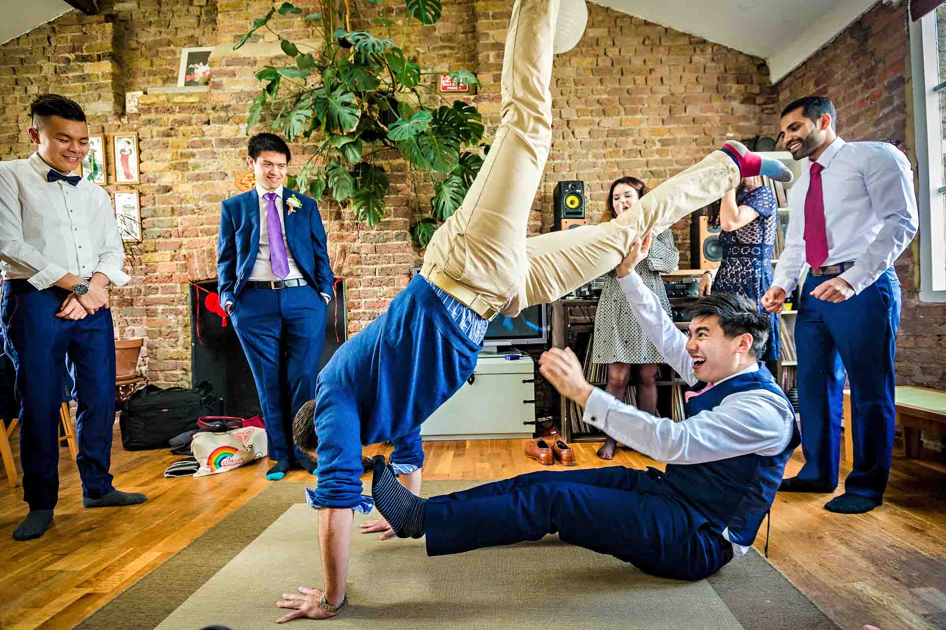 Groom sitting on floor lifting friend in the air by leg