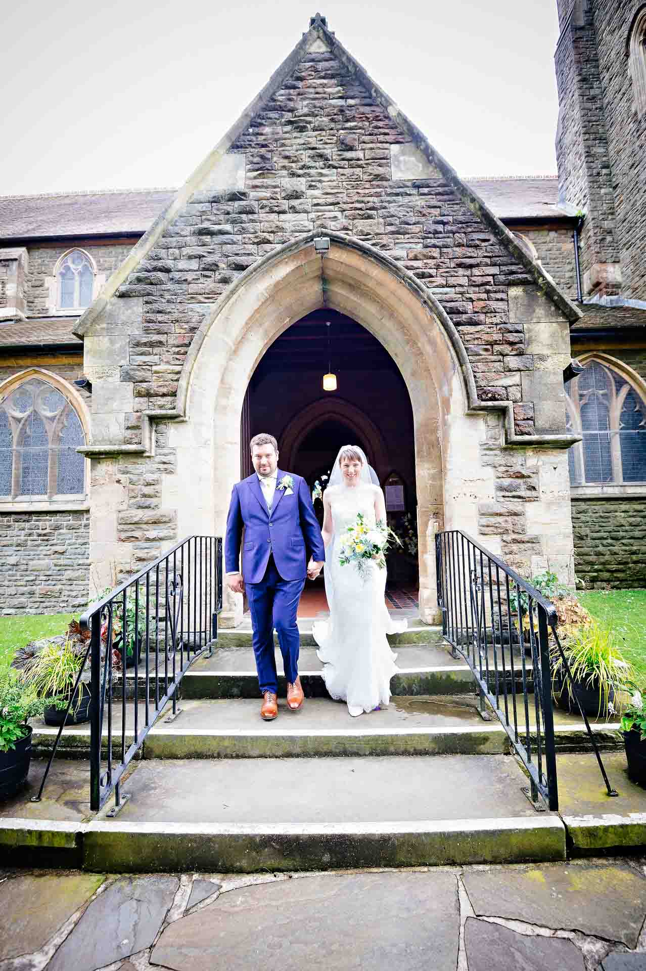 Bride and Groom Walk Out of Door of St Martin's Church in Caerphilly after Wedding