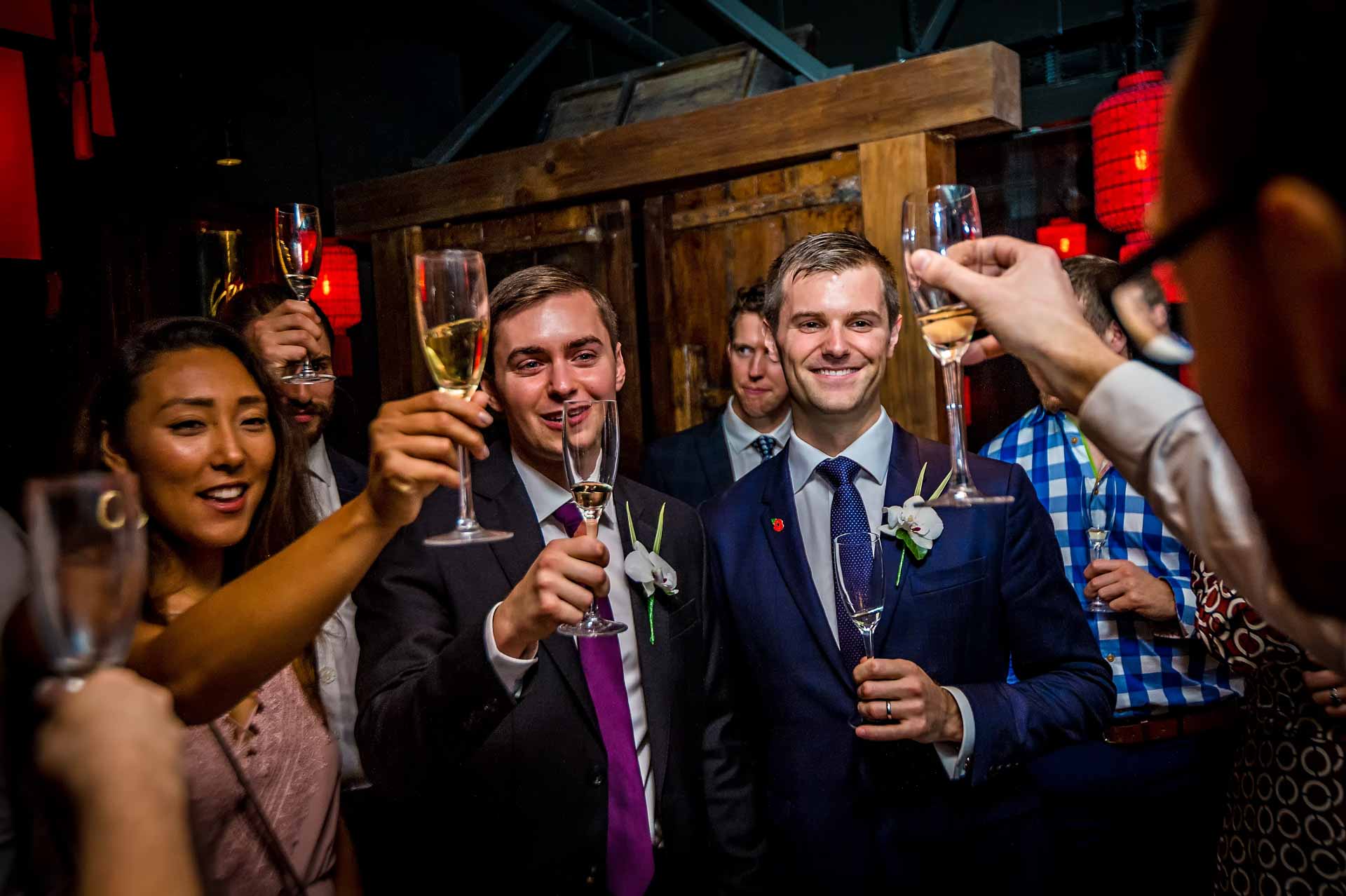 Gay Wedding Photographer Guests at wedding toasting gay couple