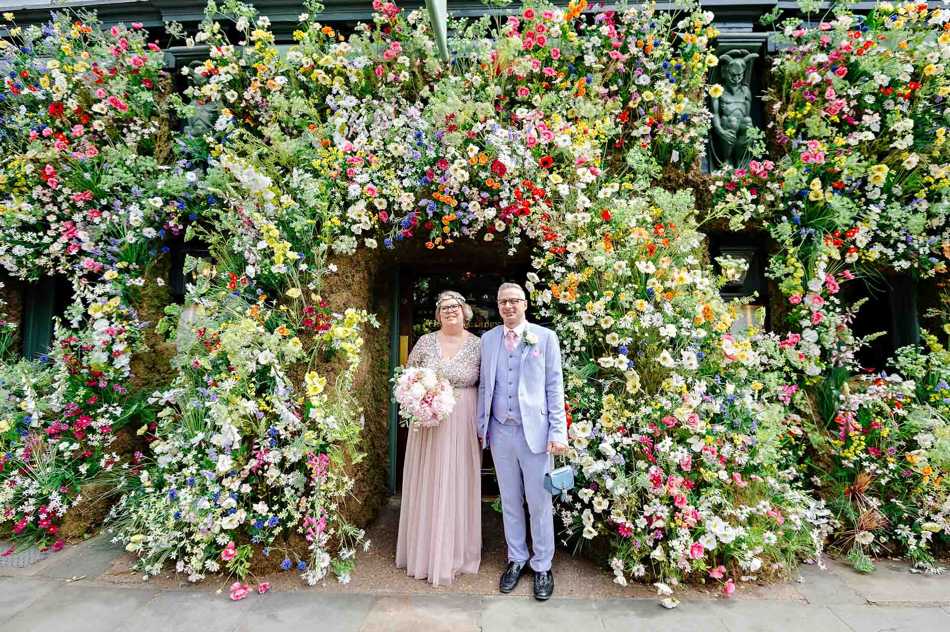 Floral wedding portrait of mature couple outside the Ivy Restaurant in Chelsea