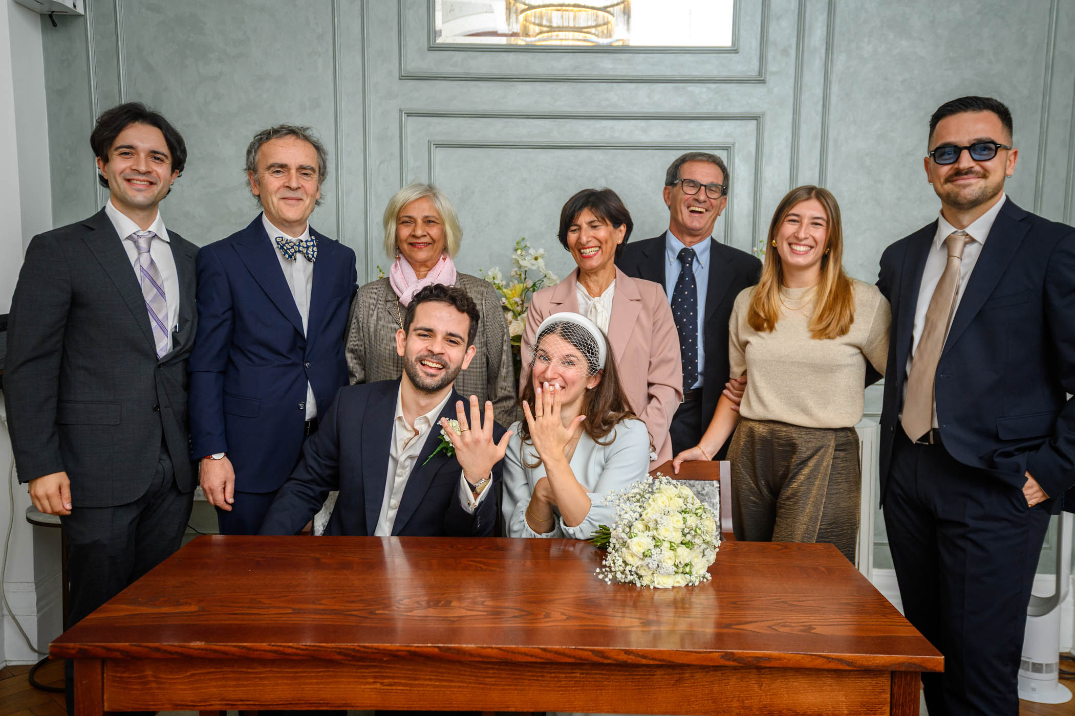 Newlyweds showing off rings with family gathered around them in the Rossetti Room