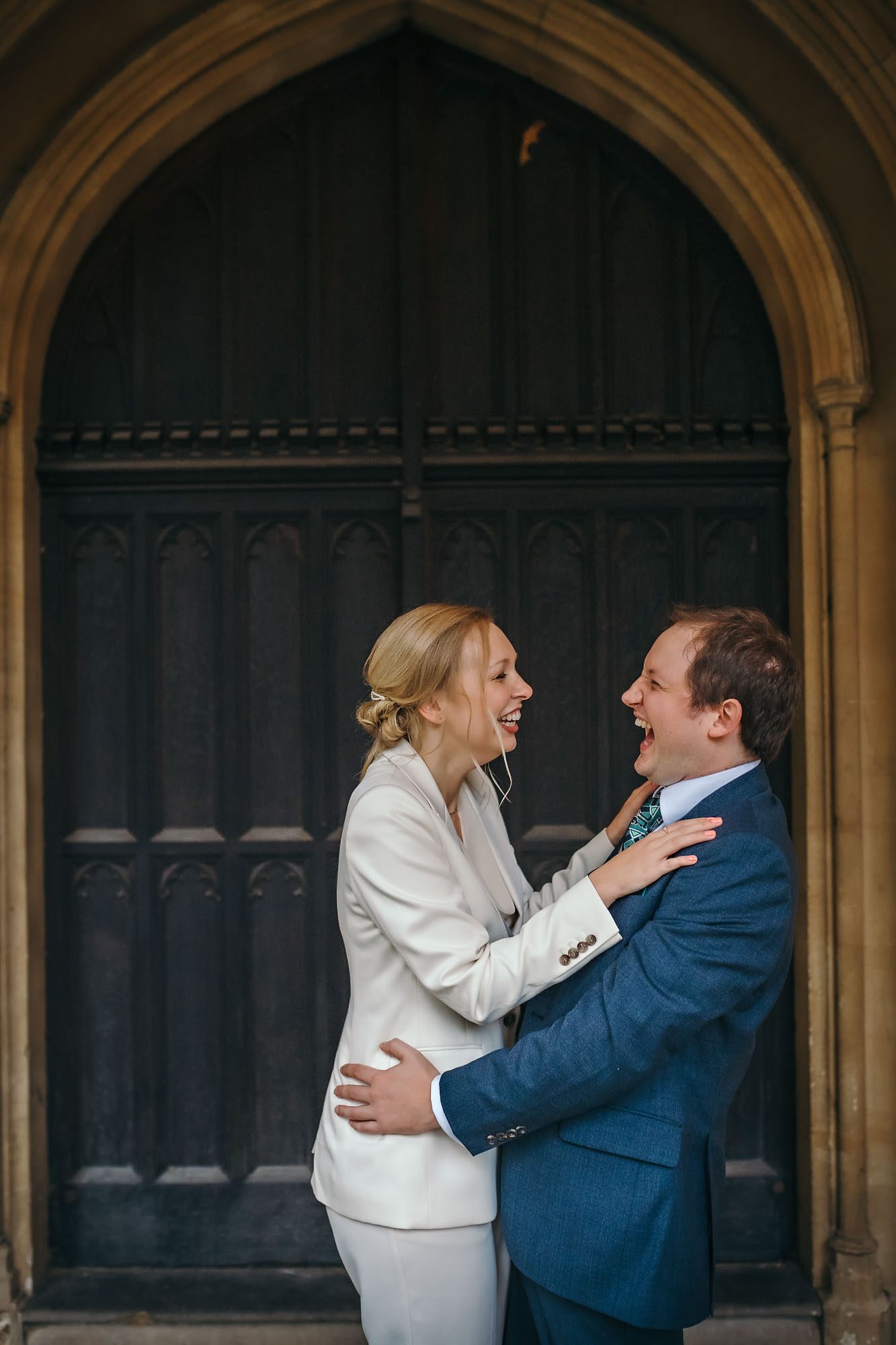 Newly-weds laughing in front of large door to St Luke's Church, Chelsea
