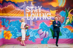 Bride and groom in front of vibrant &#039;Stay Loving&#039; mural in Chelsea, London