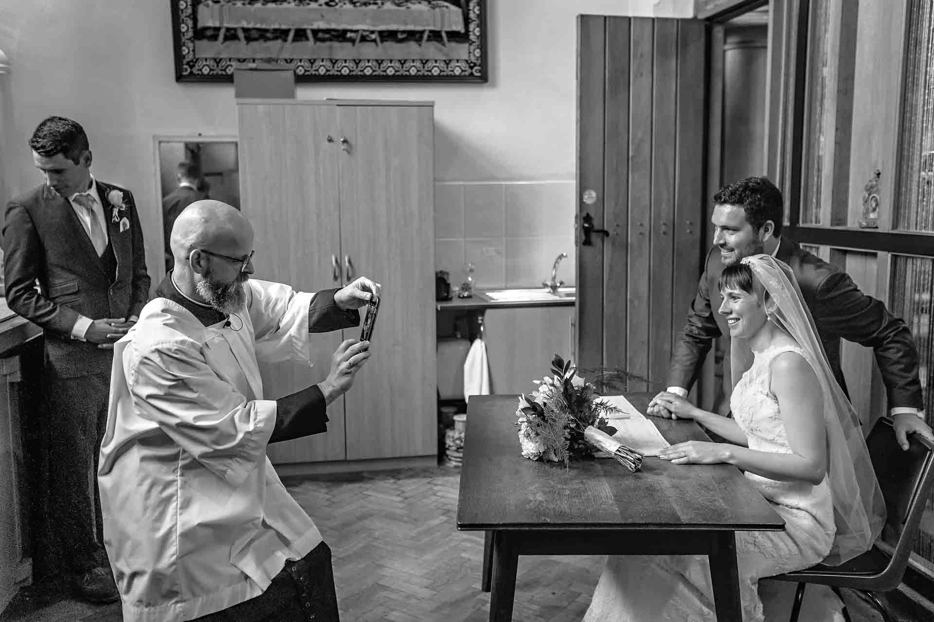 Vicar Taking Photo of Couple at St Martin's Church Wedding in Caerphilly