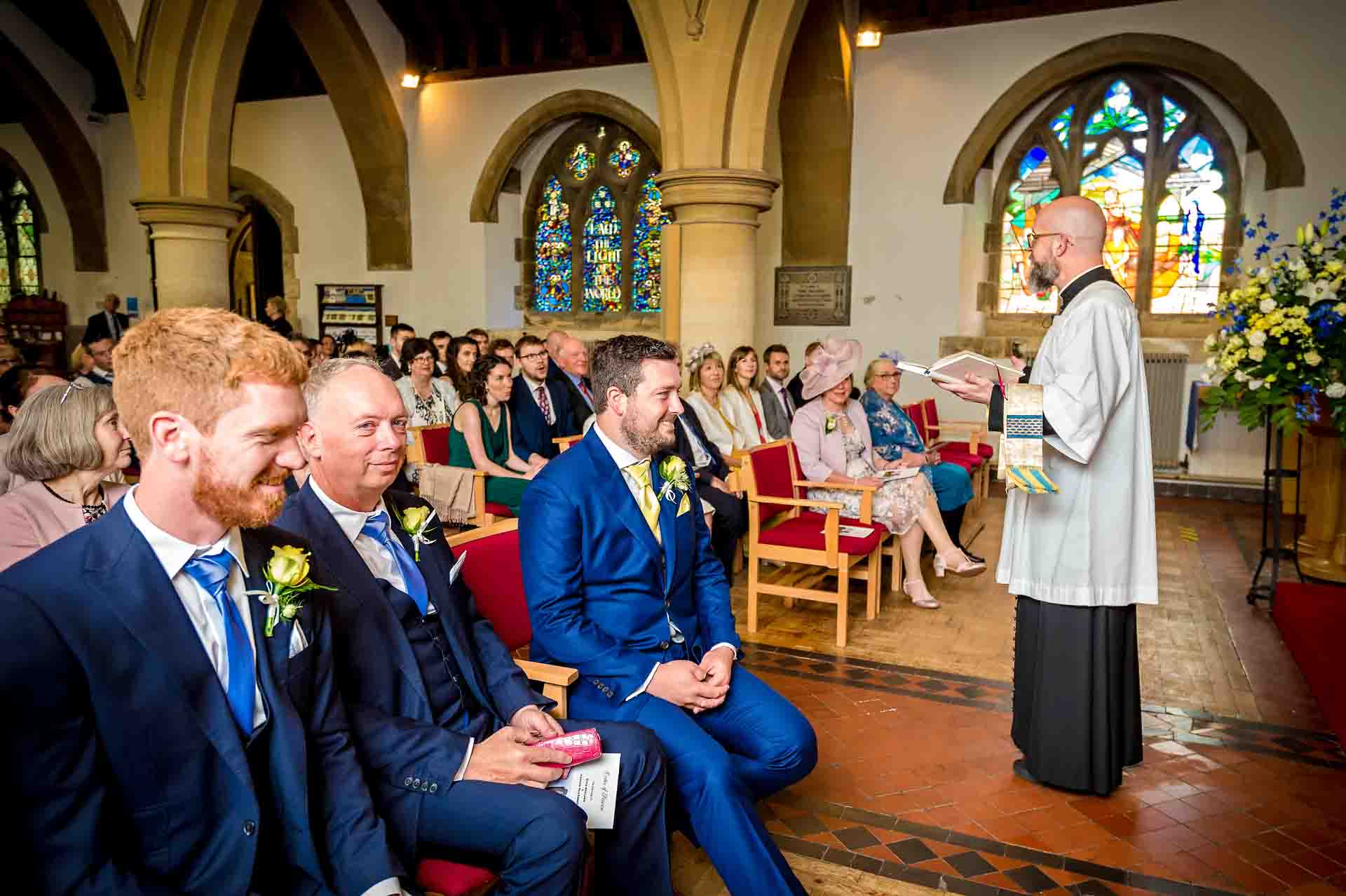 Groom and groomsmen listening to vicar at St Martins Church wedding in Caerphilly