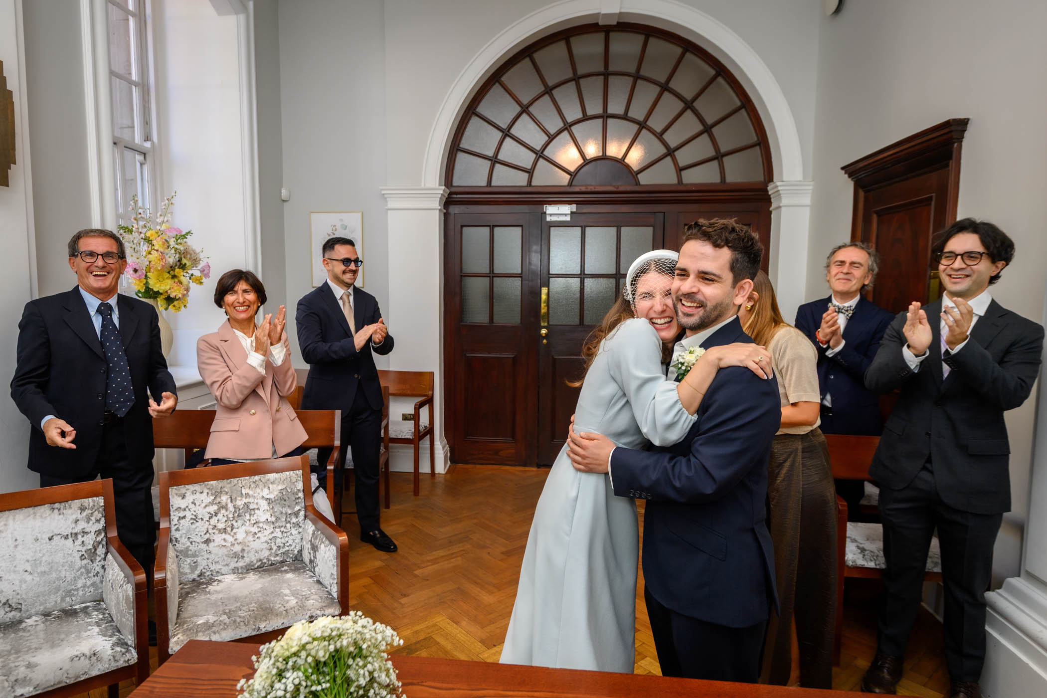 Couple hugging and laughing while guests watch in the Rossetti Room