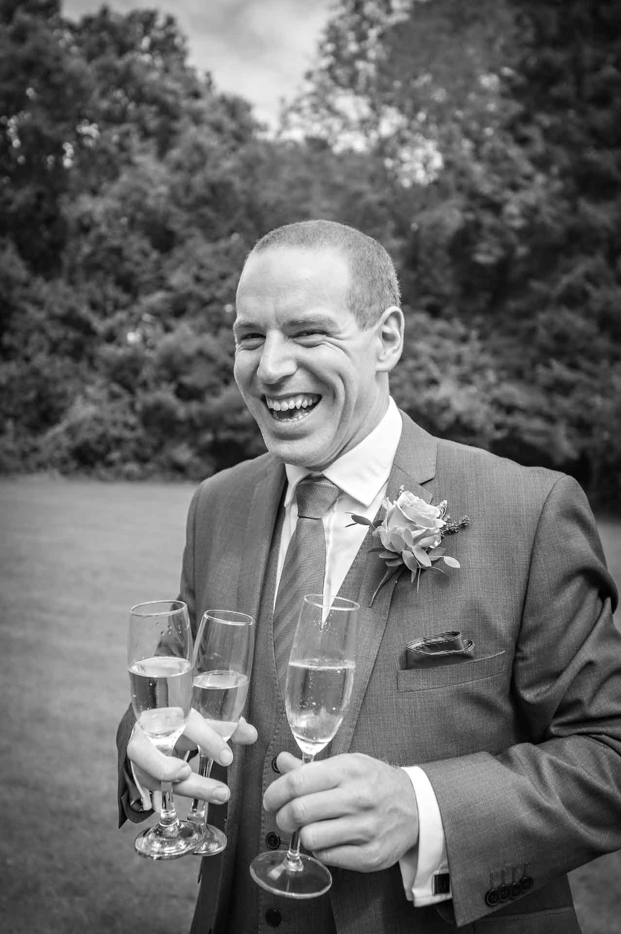 Wedding guest holding three glasses of wine and laughing