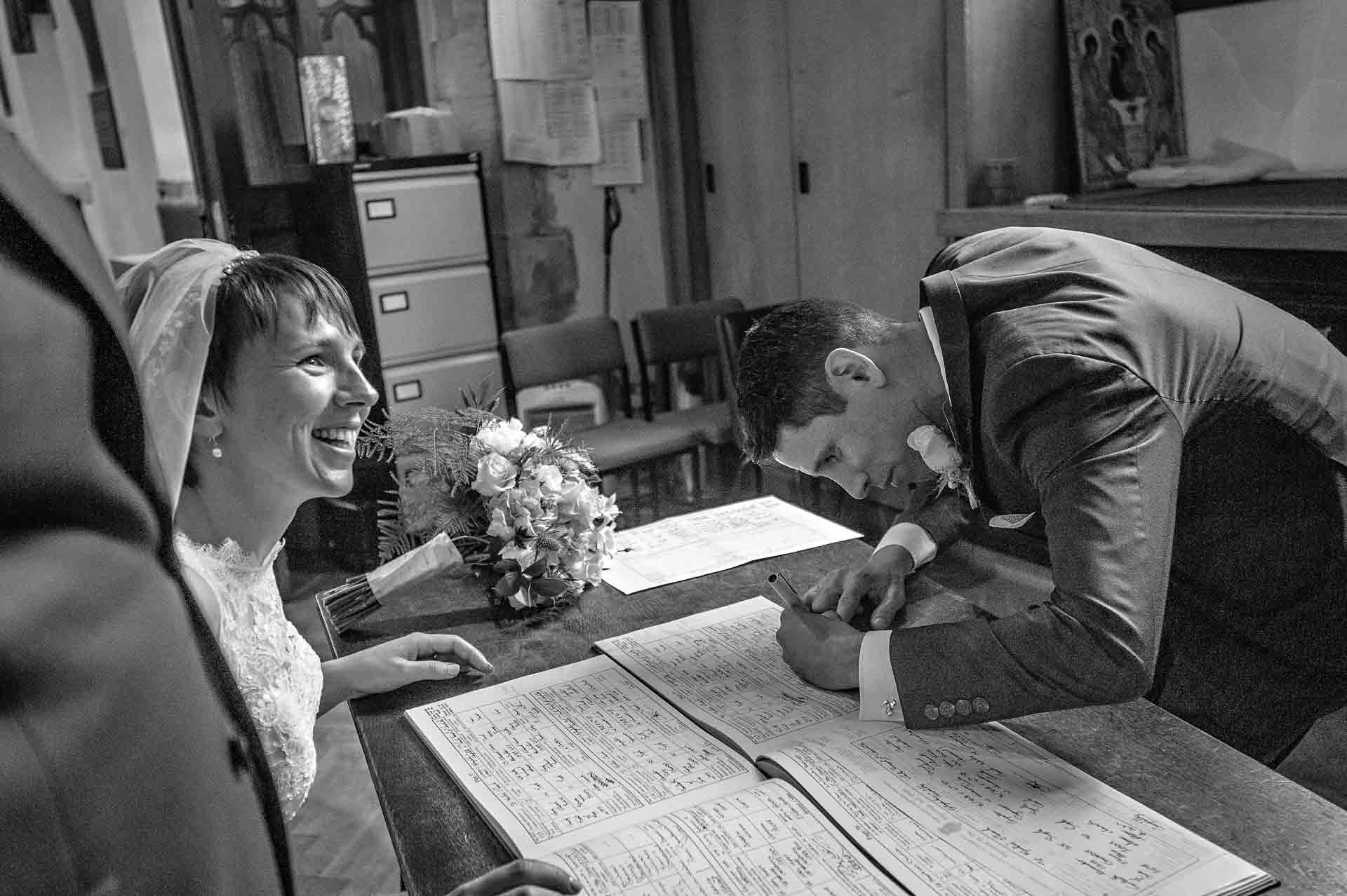 Bride smiling as witness signs register at her Welsh wedding