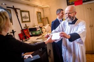 Vicar hands over wedding certificate with a smile at St Martin's Church in Caerphilly