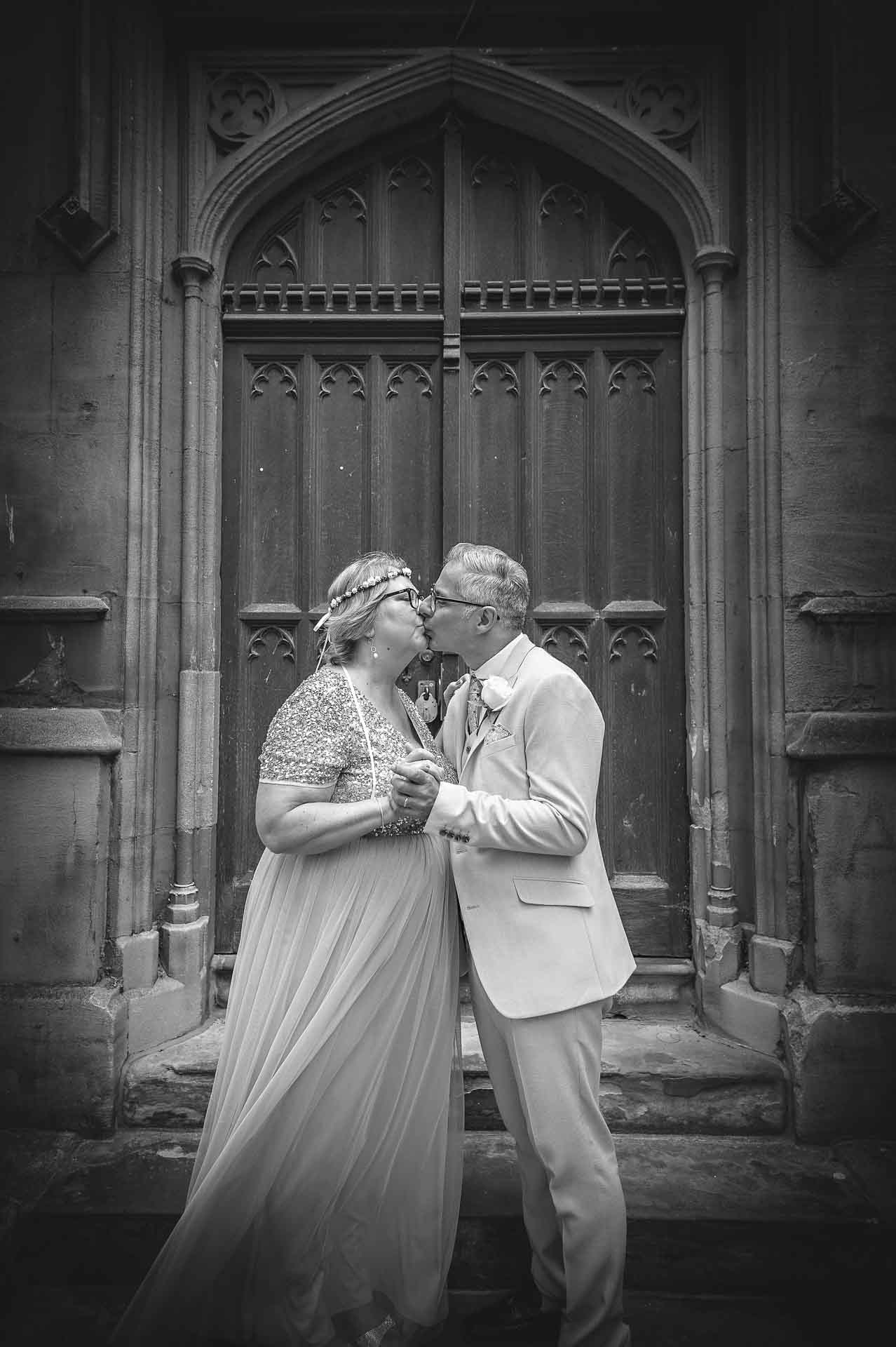 Mature wedding couple kissing outside St Luke's Church in Chelsea