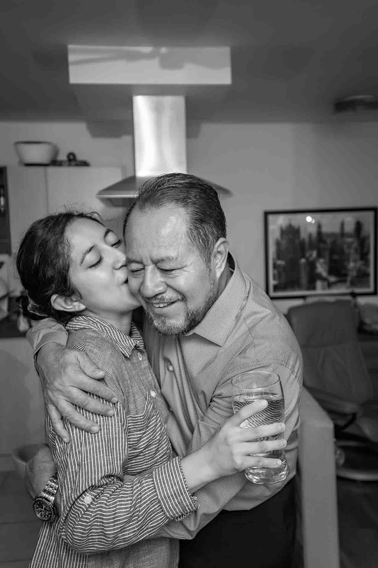 Bride kissing smiling father on cheek at preparations